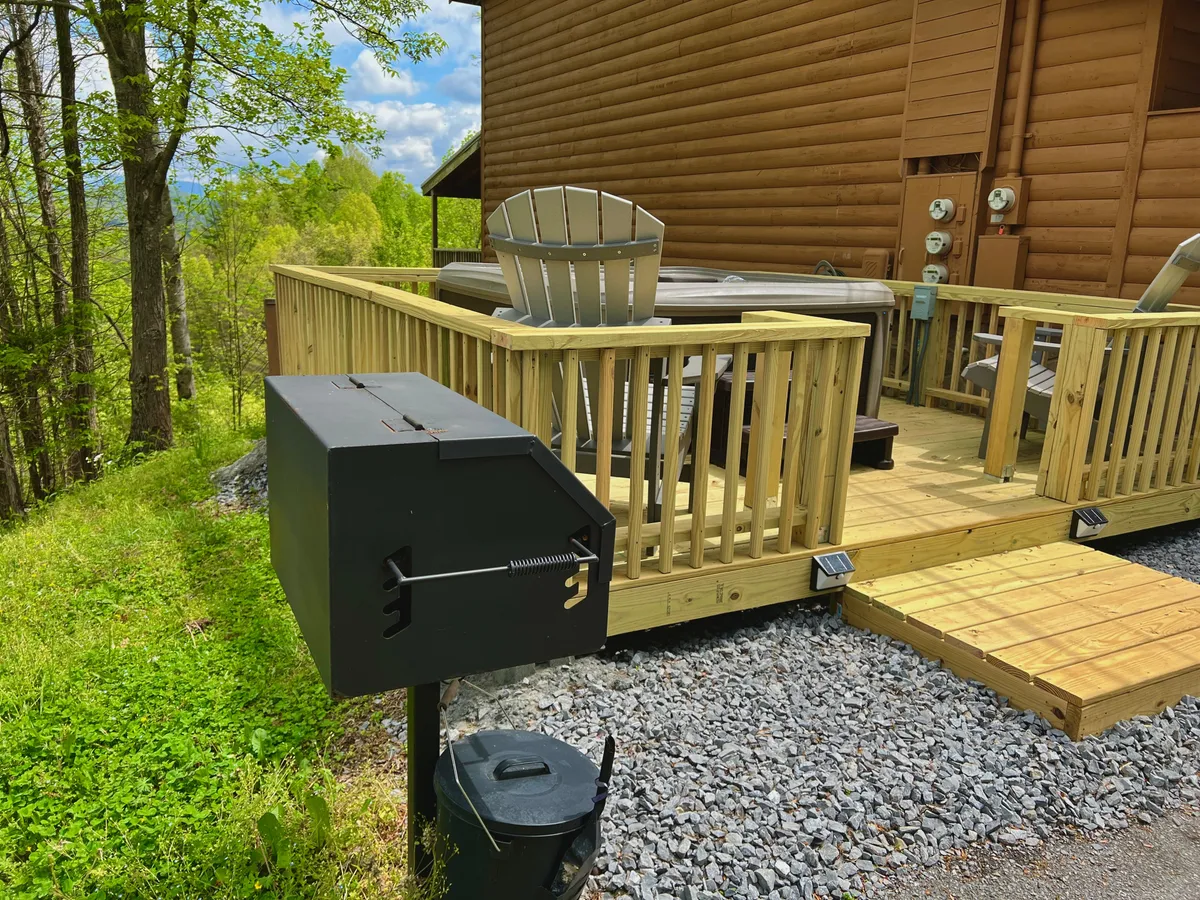 An inviting deck scene showcasing a grill, deck chairs, a bubbling hot tub, and rustic wooden railings. The setup is ideal for outdoor feasts, social gatherings, and enjoying the fresh Tennessee air. The view from the deck hints at scenic mountain surroundings.
