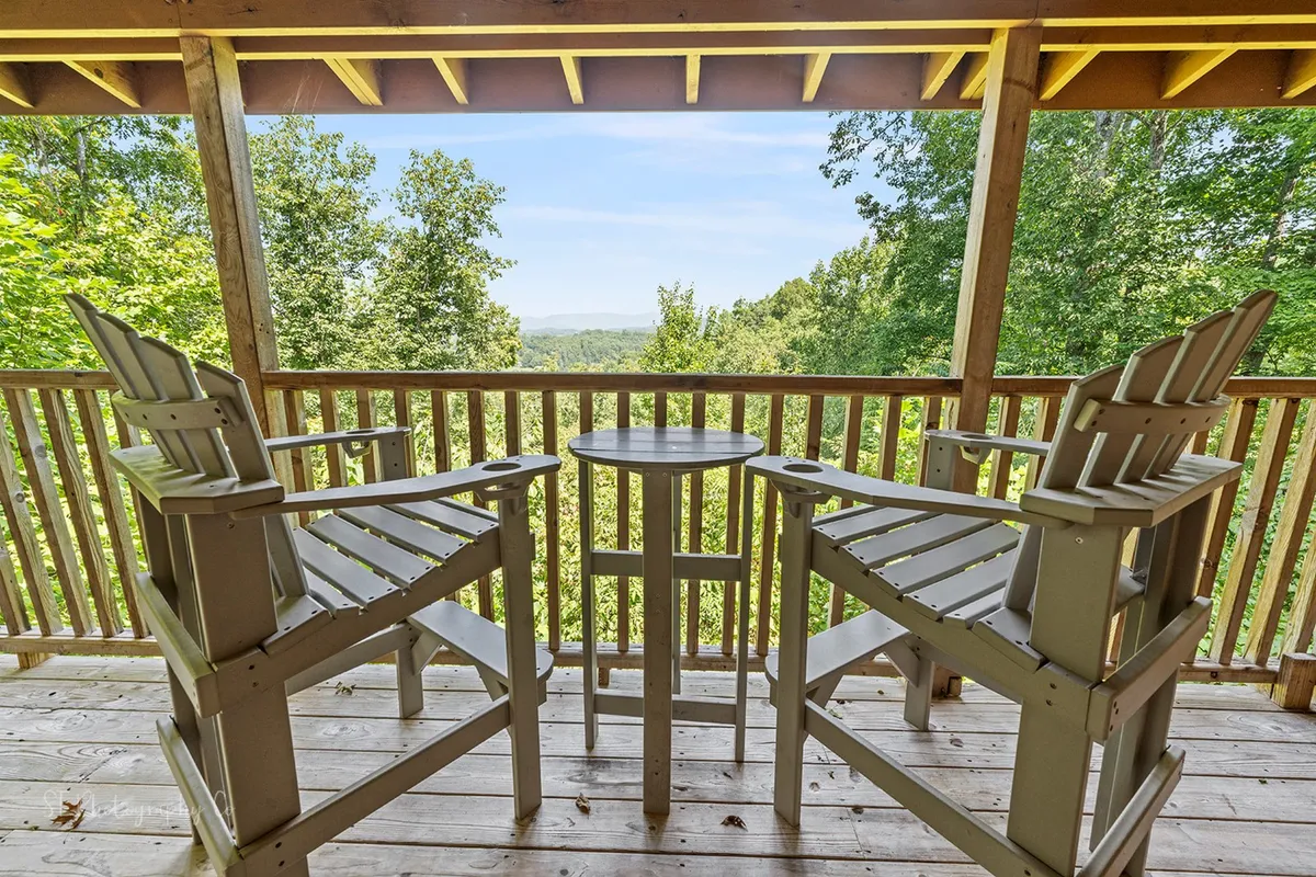 A calm outdoor seating area with wooden chairs and a circular table, offering an unobstructed view of the surrounding landscape. The setting invites guests to relax, socialize, or enjoy a morning coffee while taking in the natural beauty.